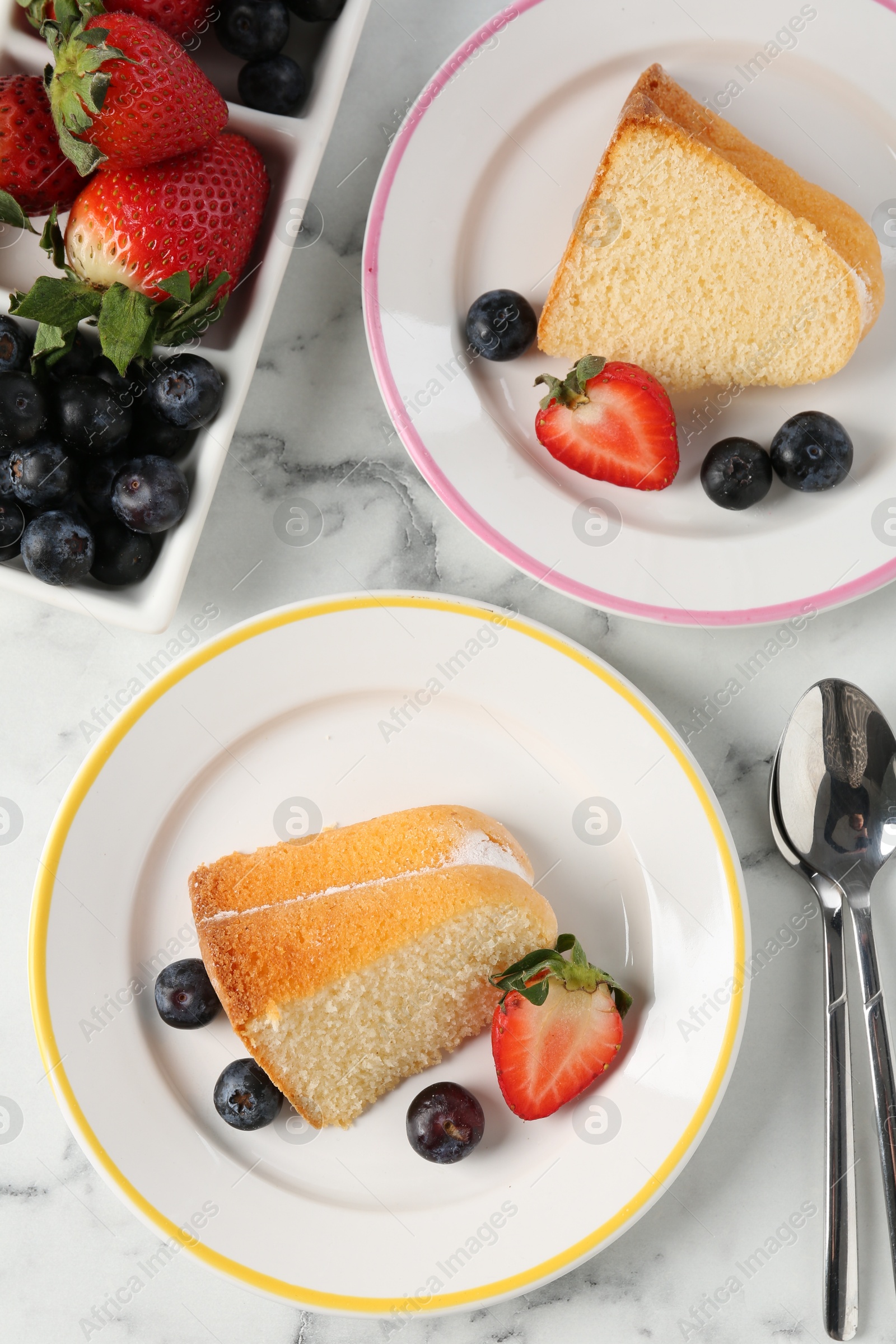 Pieces of tasty bundt cake with berries on white marble table, flat lay Photo of Pieces of tasty bundt cake with berries on white marble table, flat lay