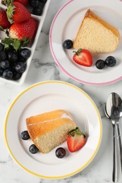 Photo of Pieces of tasty bundt cake with berries on white marble table, flat lay