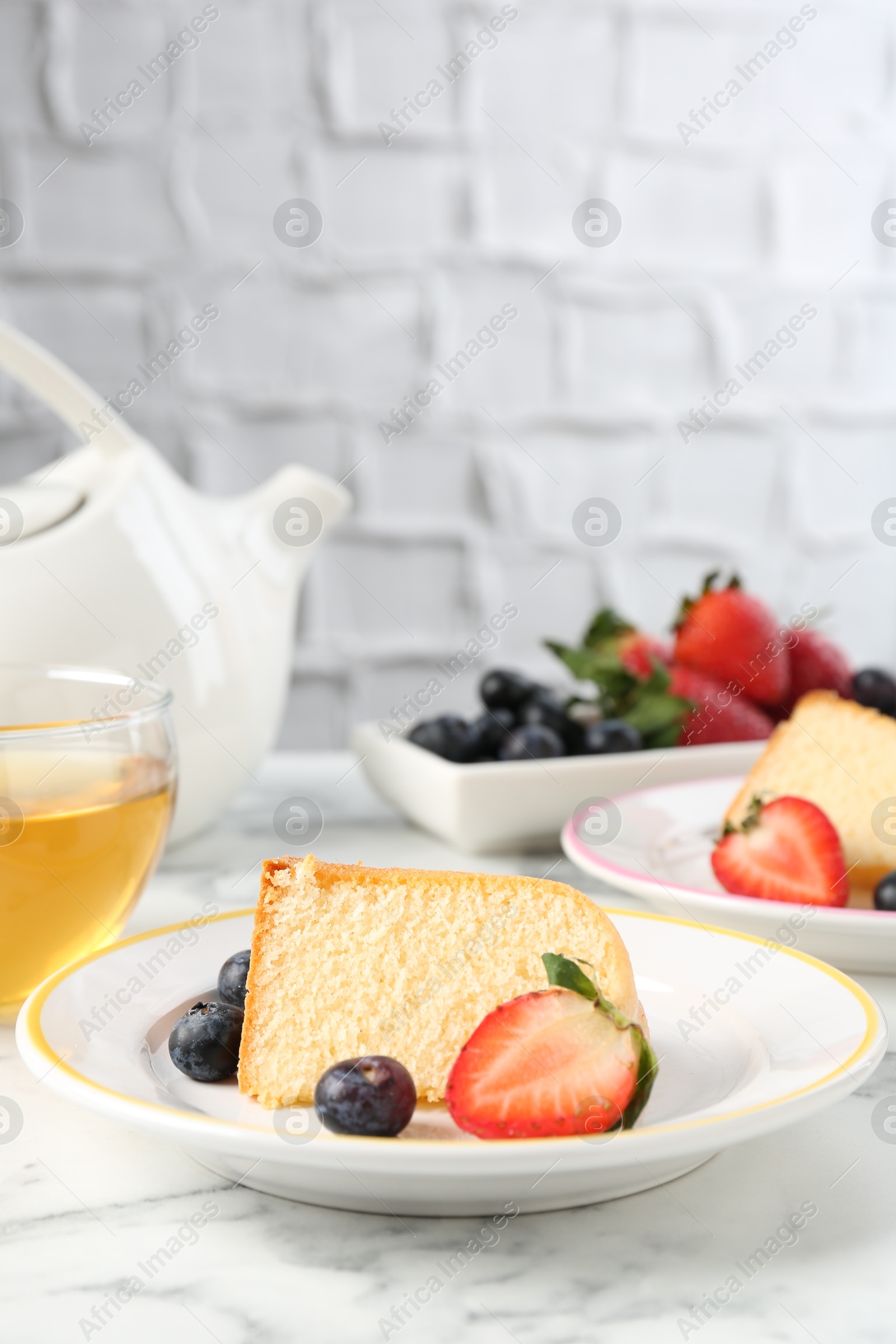 Pieces of tasty bundt cake with berries and tea on white marble table, closeup Photo of Pieces of tasty bundt cake with berries and tea on white marble table, closeup