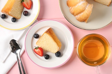 Photo of Pieces of tasty bundt cake with berries and tea on pink wooden table, flat lay