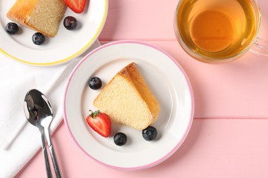 Photo of Pieces of tasty bundt cake with berries and tea on pink wooden table, flat lay