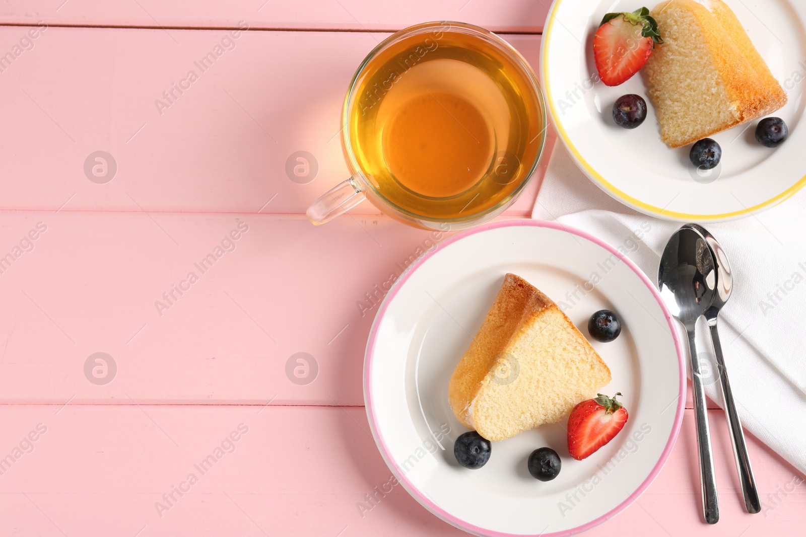 Pieces of tasty bundt cake with berries and tea on pink wooden table, flat lay. Space for text Photo of Pieces of tasty bundt cake with berries and tea on pink wooden table, flat lay. Space for text