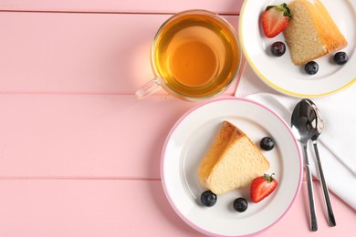 Photo of Pieces of tasty bundt cake with berries and tea on pink wooden table, flat lay. Space for text