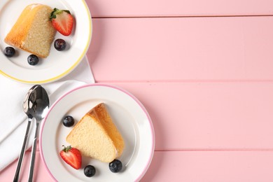 Photo of Pieces of tasty bundt cake with berries on pink wooden table, flat lay. Space for text