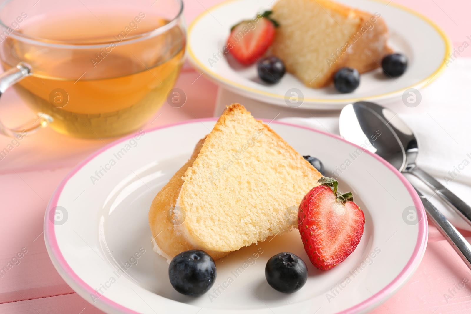 Pieces of tasty bundt cake with berries and tea on pink wooden table, closeup Photo of Pieces of tasty bundt cake with berries and tea on pink wooden table, closeup
