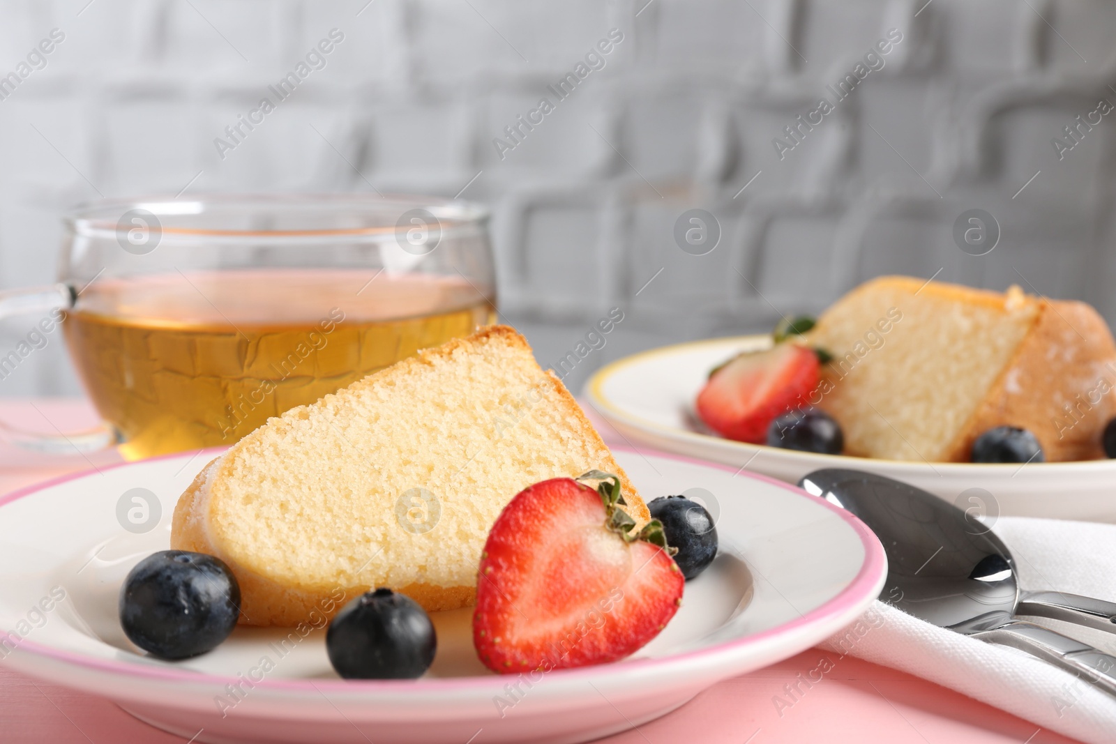 Pieces of tasty bundt cake with berries and tea on pink table, closeup Photo of Pieces of tasty bundt cake with berries and tea on pink table, closeup