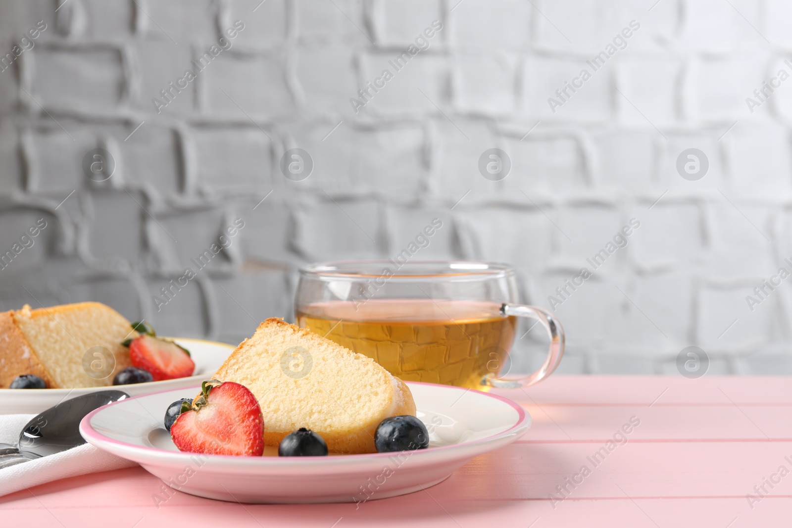 Pieces of tasty bundt cake with berries and tea on pink wooden table, closeup. Space for text Photo of Pieces of tasty bundt cake with berries and tea on pink wooden table, closeup. Space for text