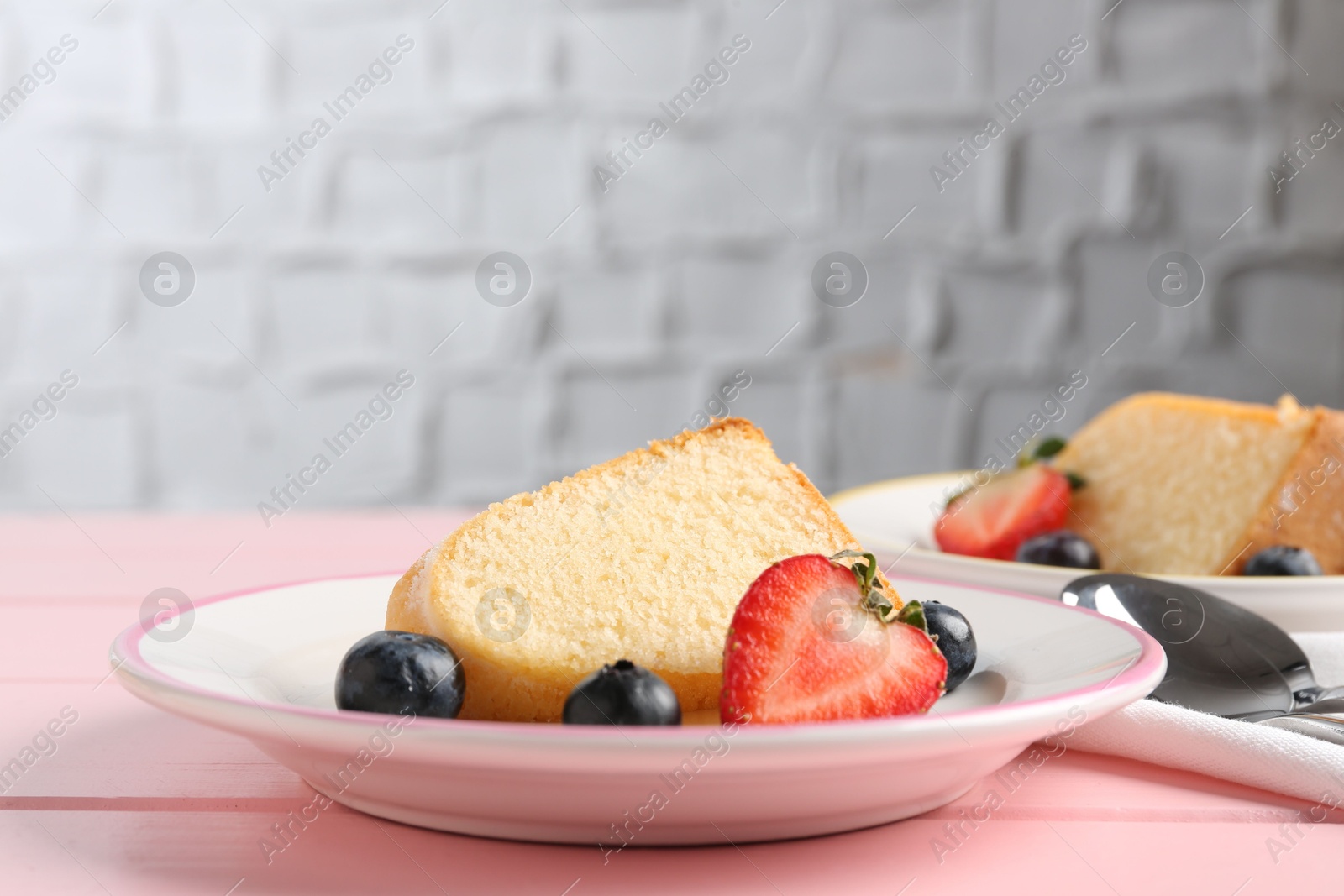 Pieces of tasty bundt cake with berries on pink wooden table, closeup Photo of Pieces of tasty bundt cake with berries on pink wooden table, closeup