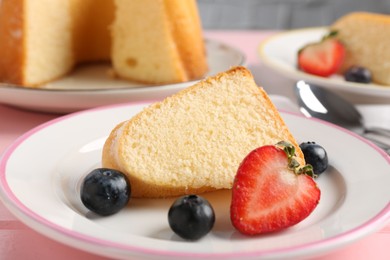Photo of Piece of tasty bundt cake with berries on table, closeup