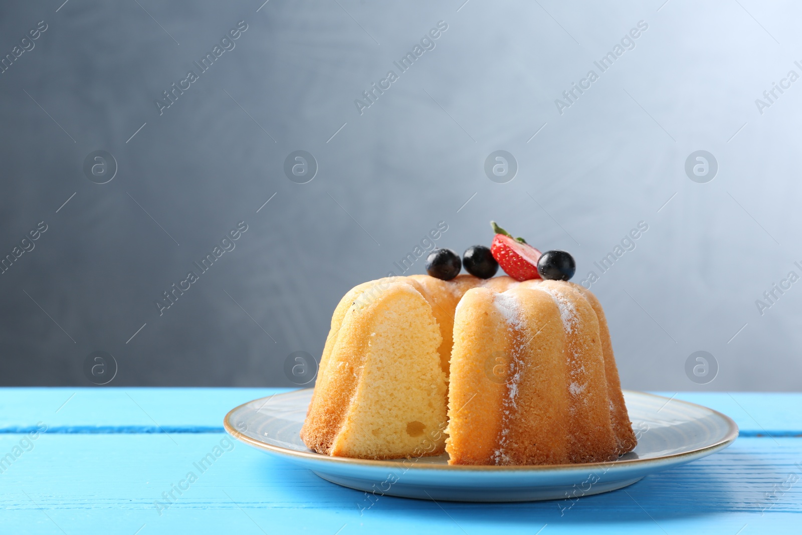 Tasty bundt cake with powdered sugar and berries on light blue wooden table, closeup. Space for text Photo of Tasty bundt cake with powdered sugar and berries on light blue wooden table, closeup. Space for text
