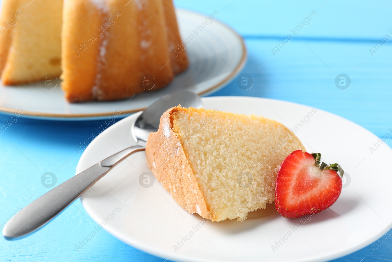 Piece of tasty bundt cake with strawberry on light blue wooden table, closeup Photo of Piece of tasty bundt cake with strawberry on light blue wooden table, closeup