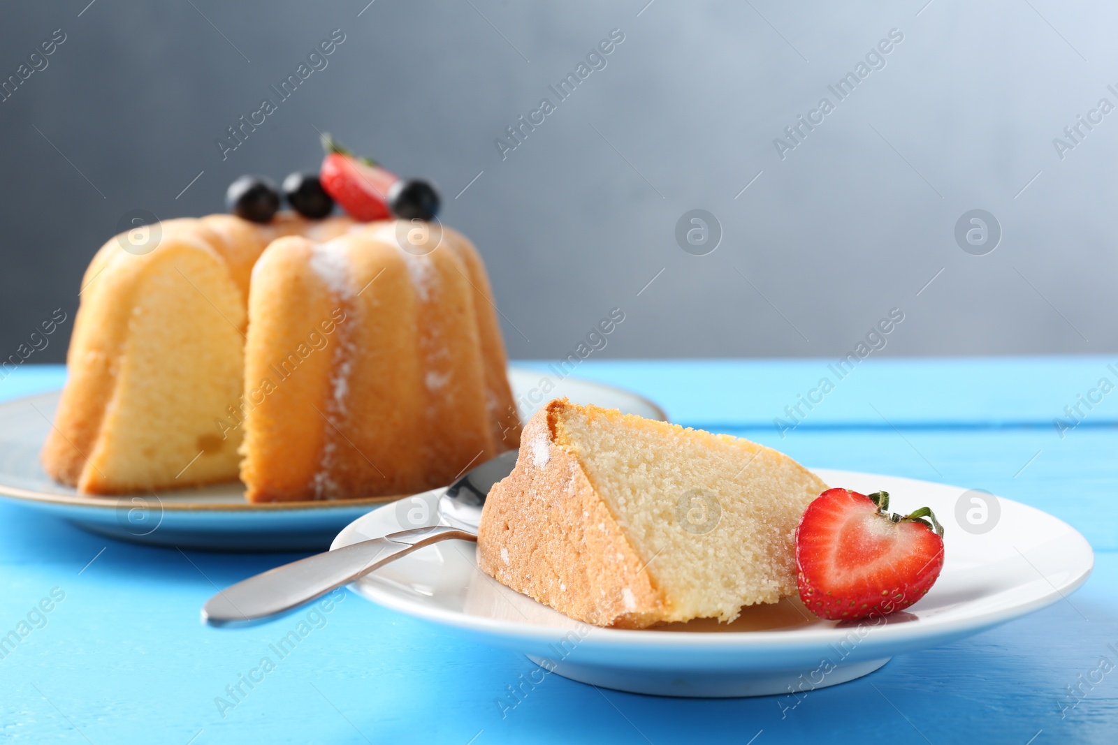 Tasty bundt cake with powdered sugar and berries on light blue wooden table, closeup Photo of Tasty bundt cake with powdered sugar and berries on light blue wooden table, closeup