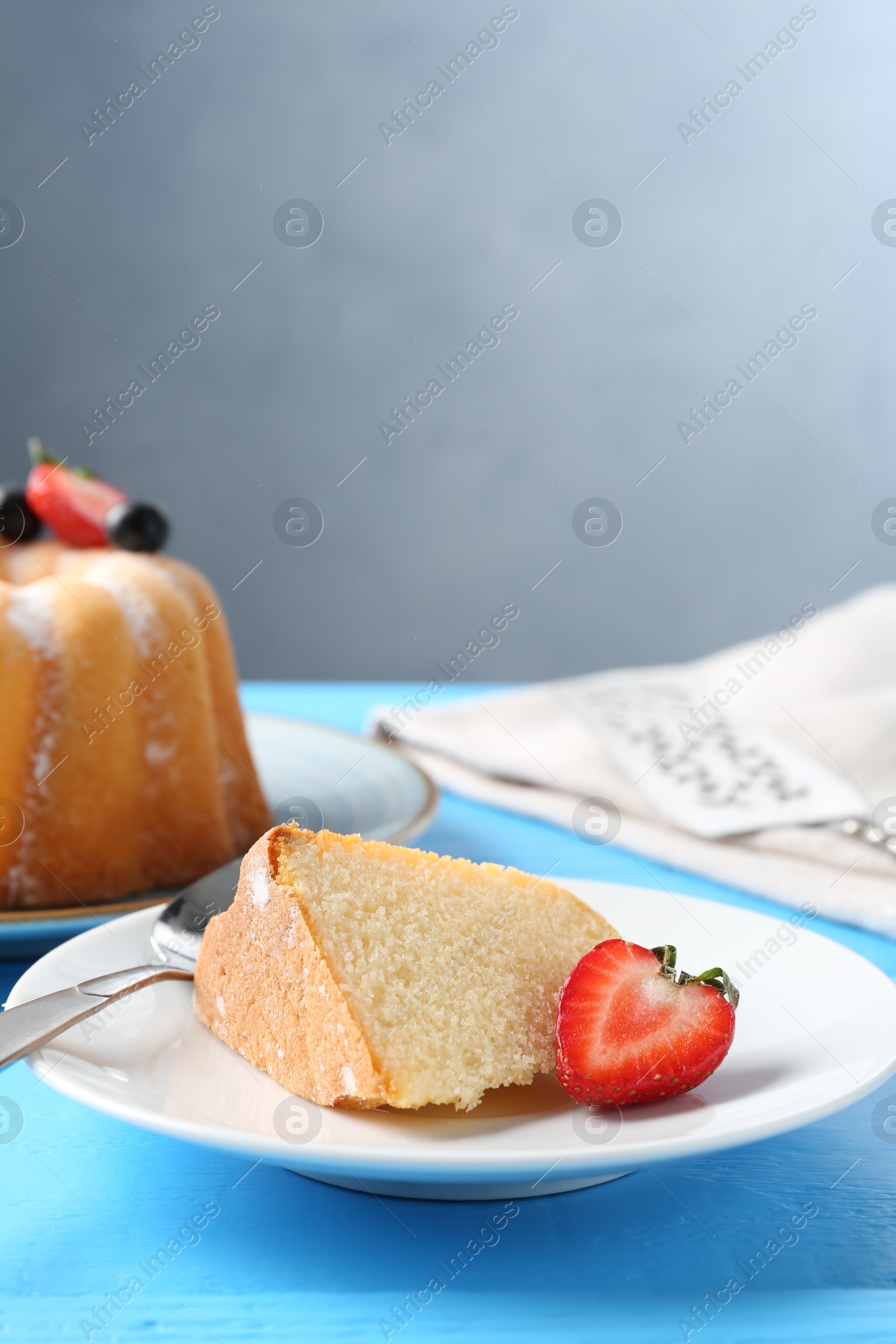 Piece of tasty bundt cake with strawberry on light blue wooden table, closeup Photo of Piece of tasty bundt cake with strawberry on light blue wooden table, closeup