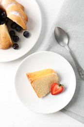 Photo of Tasty bundt cake with powdered sugar, berries and spoon on white table, flat lay