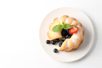 Photo of Tasty bundt cake with powdered sugar, berries and mint on white background, top view. Space for text