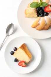 Photo of Tasty bundt cake with powdered sugar, berries and mint on white table, flat lay