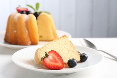 Photo of Tasty bundt cake with powdered sugar, berries and mint on white table, closeup