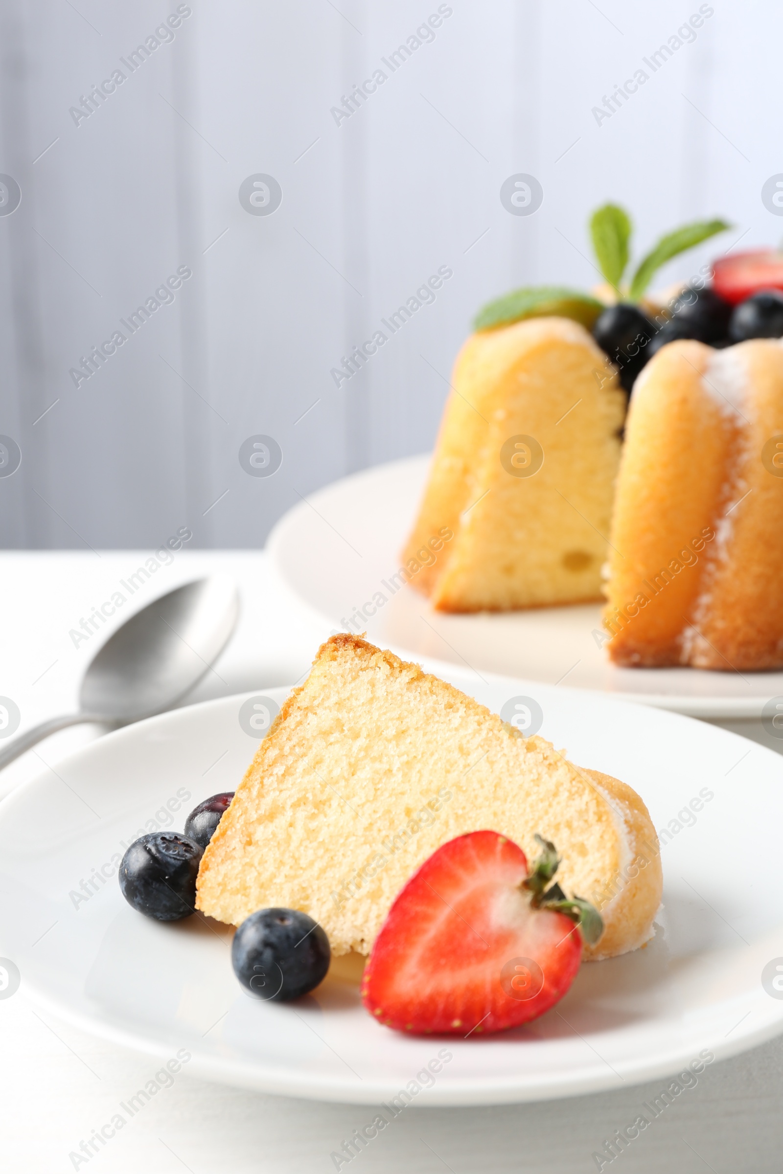 Tasty bundt cake with powdered sugar, berries and mint on white table, closeup Photo of Tasty bundt cake with powdered sugar, berries and mint on white table, closeup