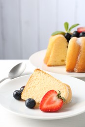 Photo of Tasty bundt cake with powdered sugar, berries and mint on white table, closeup