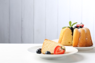 Photo of Tasty bundt cake with powdered sugar, berries and mint on white table, closeup. Space for text