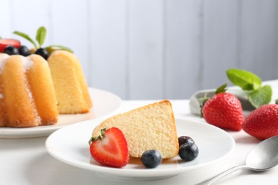 Photo of Tasty bundt cake with powdered sugar, berries and mint on white table, closeup