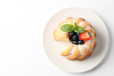 Photo of Tasty bundt cake with powdered sugar, berries and mint on white table, top view. Space for text