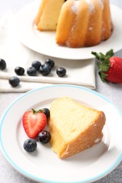 Photo of Piece of tasty bundt cake with berries on table, closeup