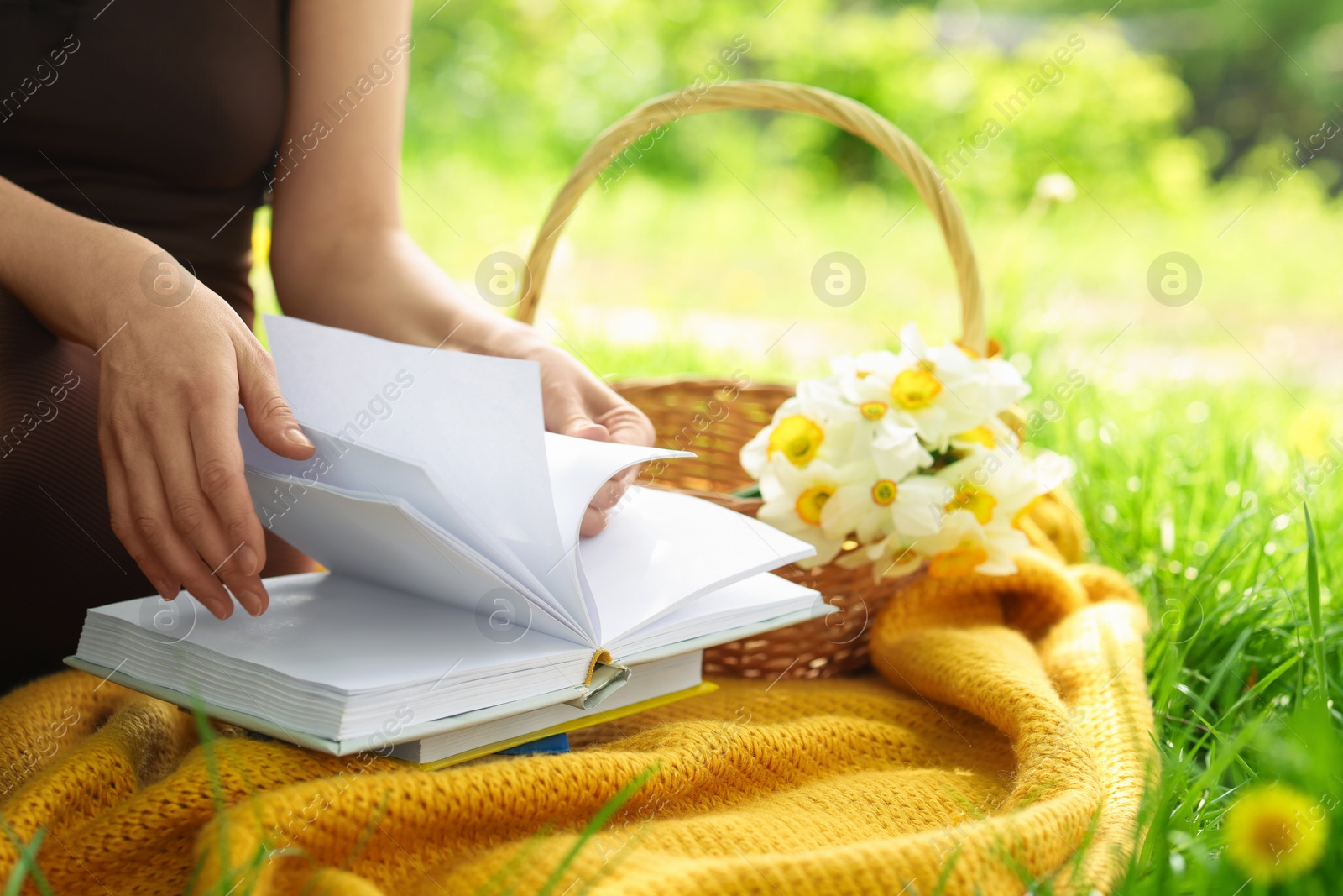 Woman reading book on blanket outdoors, closeup Photo of Woman reading book on blanket outdoors, closeup