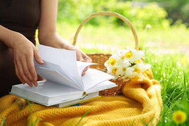Photo of Woman reading book on blanket outdoors, closeup