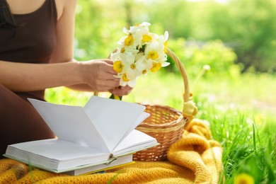 Photo of Woman reading book on blanket outdoors, closeup