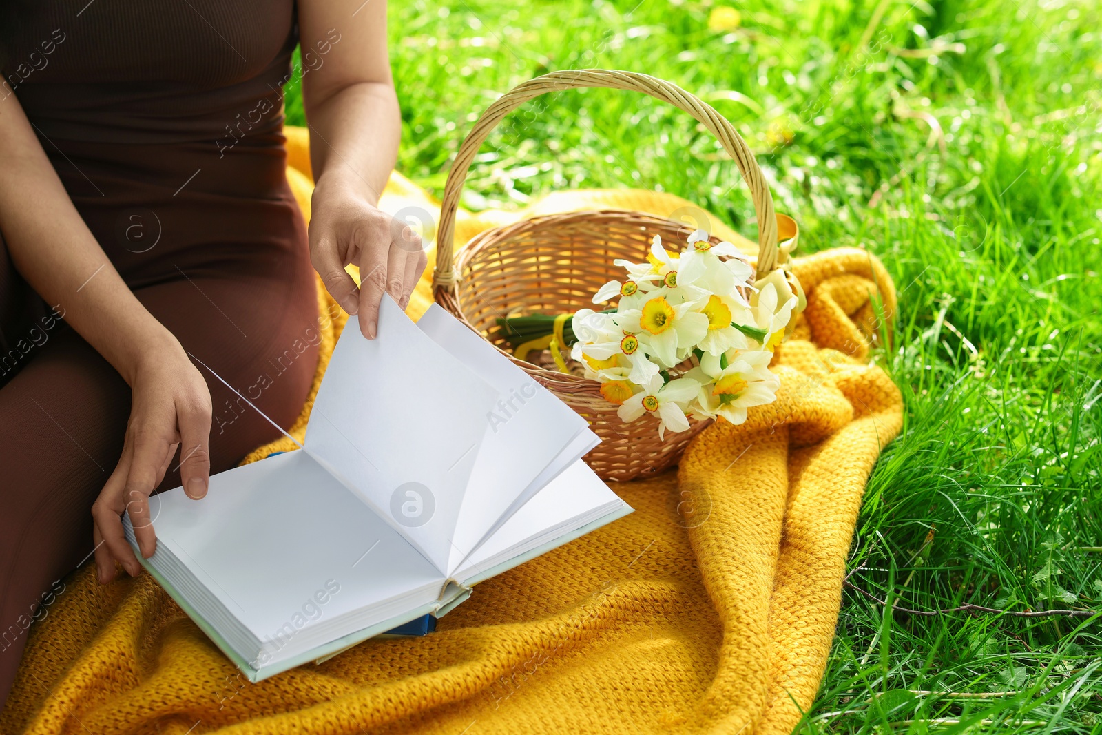 Woman reading book on blanket outdoors, closeup Photo of Woman reading book on blanket outdoors, closeup