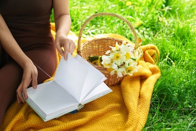 Photo of Woman reading book on blanket outdoors, closeup