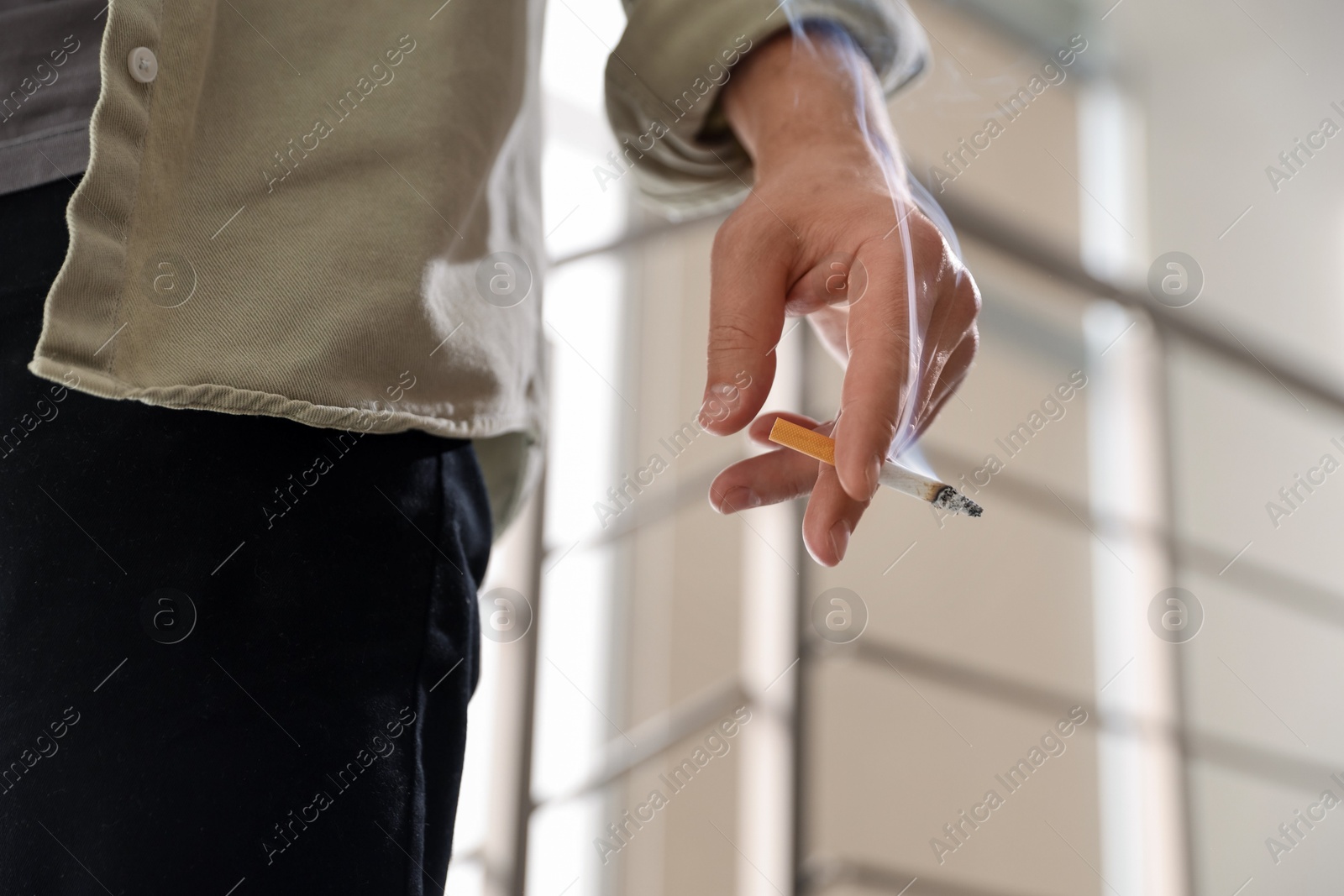 Man with cigarette on blurred background, closeup Photo of Man with cigarette on blurred background, closeup