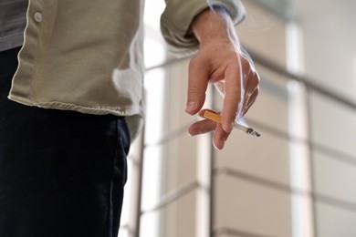 Photo of Man with cigarette on blurred background, closeup