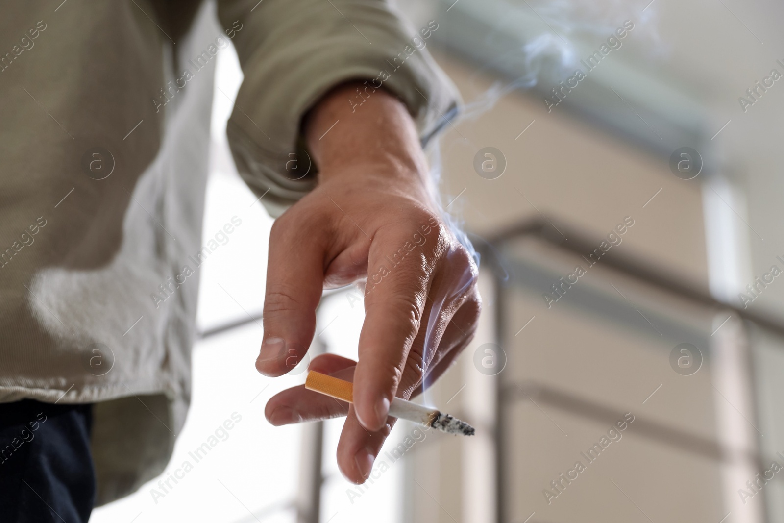 Man with cigarette on blurred background, closeup Photo of Man with cigarette on blurred background, closeup