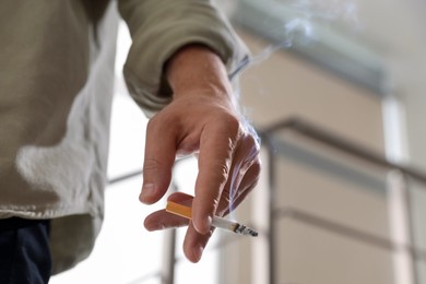 Photo of Man with cigarette on blurred background, closeup