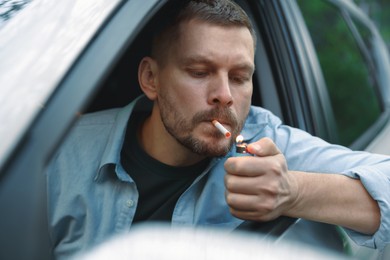 Photo of Man lighting cigarette in car, view from outside