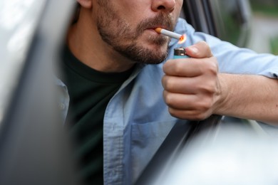Photo of Man lighting cigarette in car, closeup view