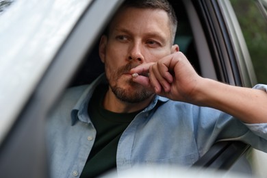 Photo of Man smoking cigarette in car, view from outside
