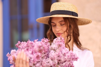 Photo of Beautiful woman in hat with bouquet of lilac flowers outdoors