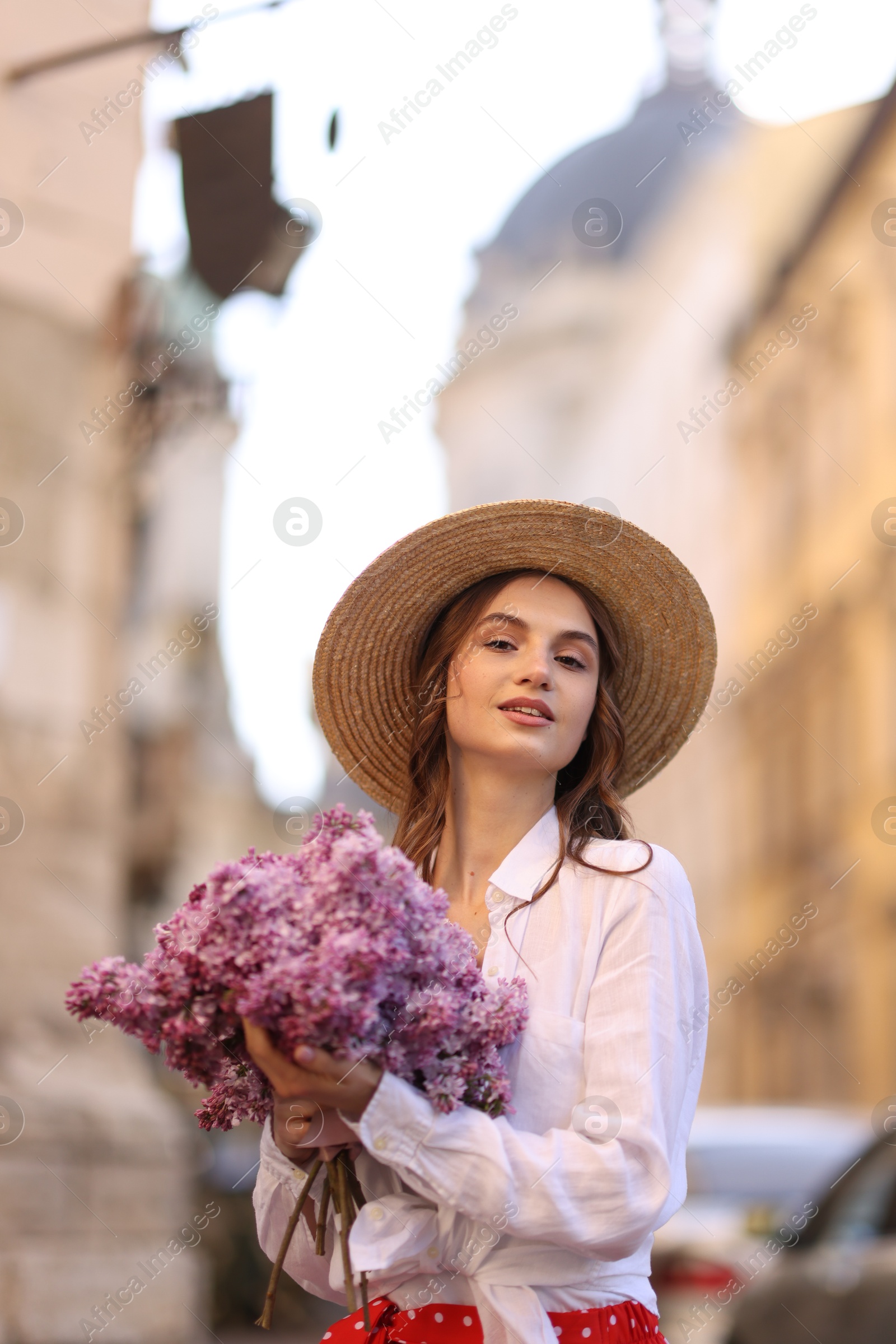 Beautiful woman in hat with bouquet of lilac flowers outdoors Photo of Beautiful woman in hat with bouquet of lilac flowers outdoors