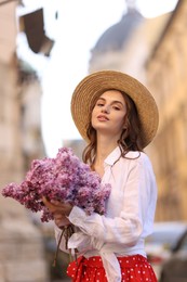 Photo of Beautiful woman in hat with bouquet of lilac flowers outdoors