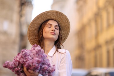 Photo of Beautiful woman in hat with bouquet of lilac flowers outdoors. Space for text