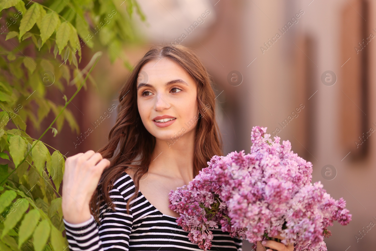 Smiling woman with bouquet of lilac flowers outdoors Photo of Smiling woman with bouquet of lilac flowers outdoors