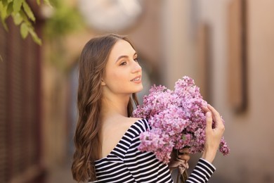 Photo of Smiling woman with bouquet of lilac flowers outdoors