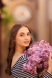 Photo of Smiling woman with bouquet of lilac flowers on blurred background