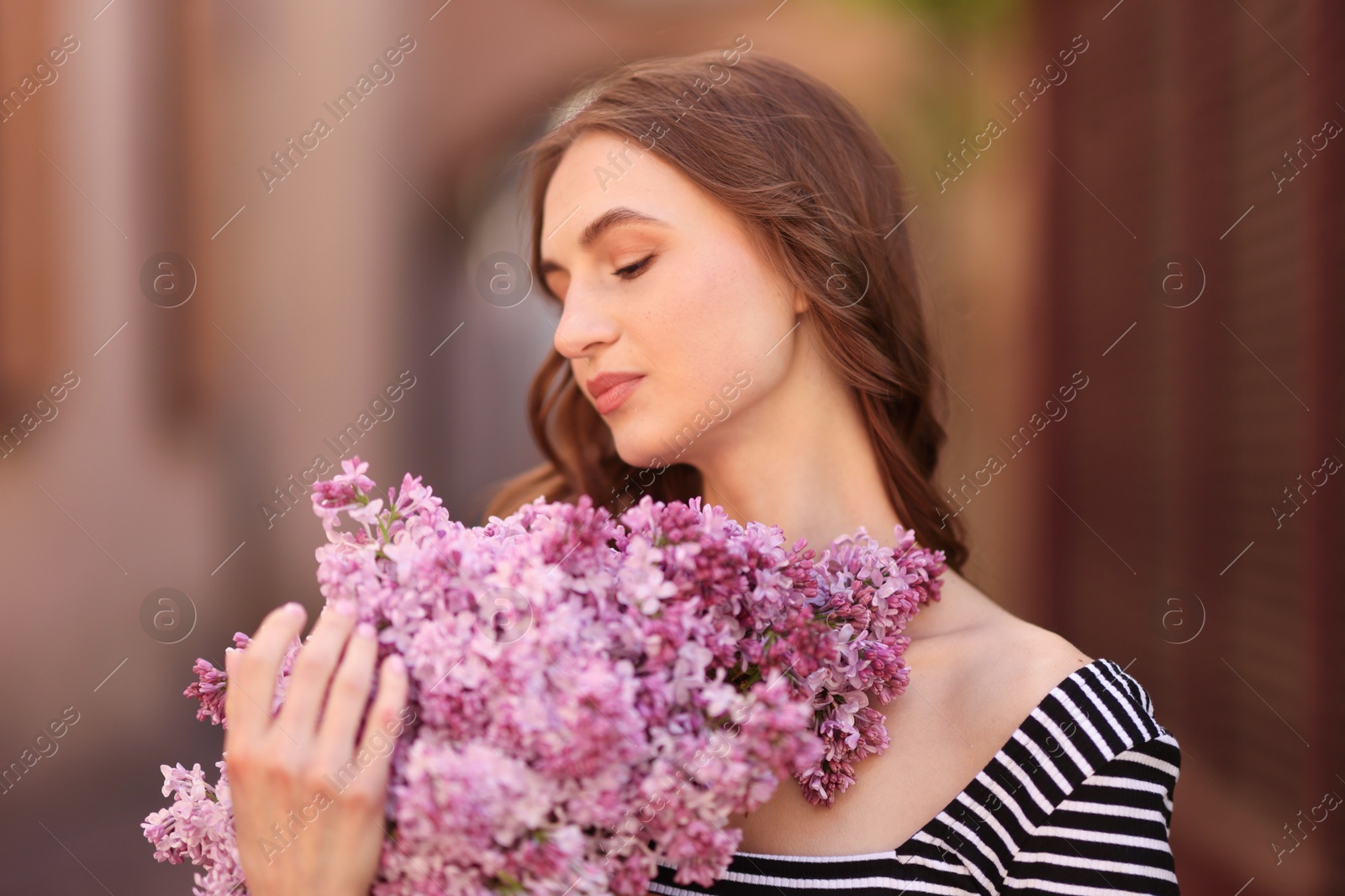 Beautiful woman with bouquet of lilac flowers on blurred background Photo of Beautiful woman with bouquet of lilac flowers on blurred background
