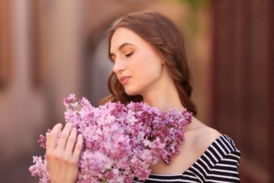 Photo of Beautiful woman with bouquet of lilac flowers on blurred background