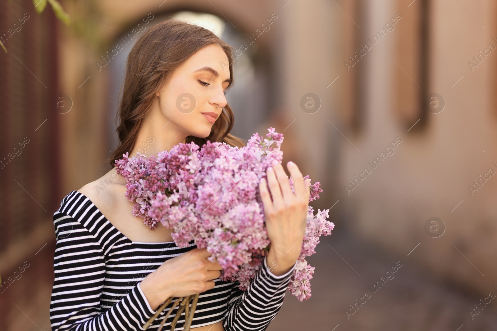 Beautiful woman with bouquet of lilac flowers outdoors. Space for text Photo of Beautiful woman with bouquet of lilac flowers outdoors. Space for text