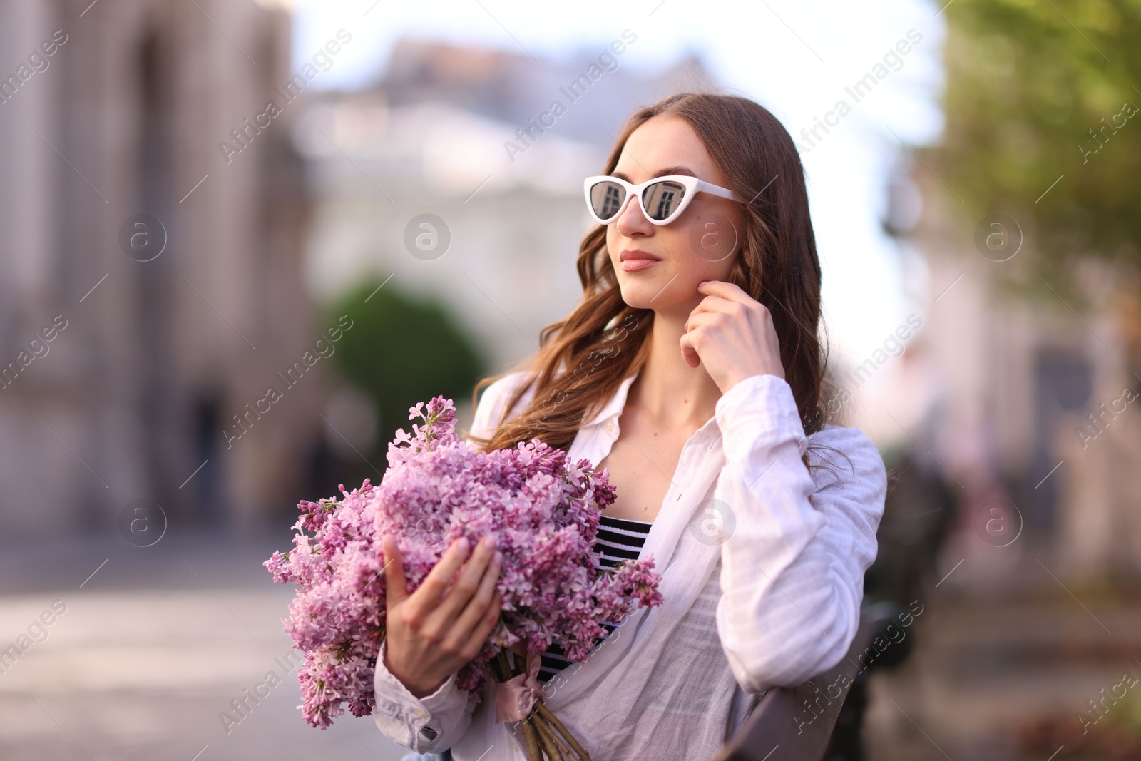 Beautiful woman in sunglasses with bouquet of lilac flowers outdoors Photo of Beautiful woman in sunglasses with bouquet of lilac flowers outdoors